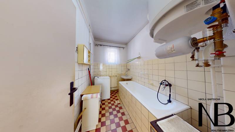 Rodinný dom s veľkým pozemkom a garážou, Dvorec - Kúpeľňa v rodinnom dome s vaňou, umývadlom, práčkou a bielym bojlerom.