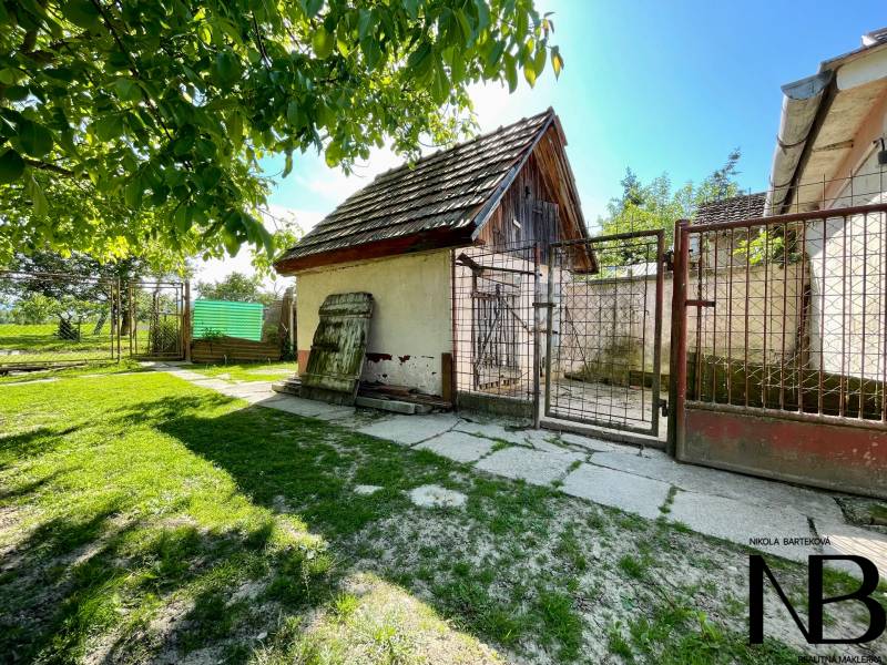 Rodinný dom s veľkým pozemkom a garážou, Dvorec - Dvor rodinného domu v Dvorci so starými budovami a zeleňou.