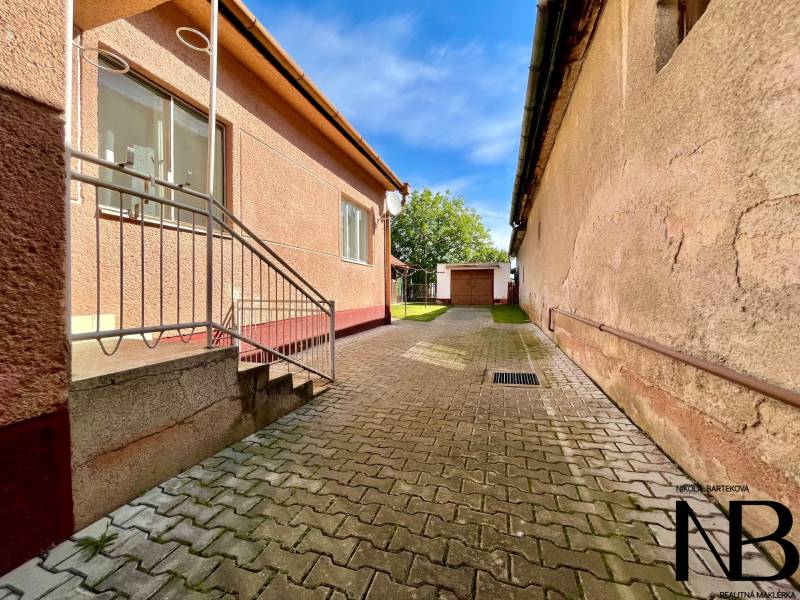Rodinný dom s veľkým pozemkom a garážou, Dvorec - Rodinný dom v Dvorci s dláždeným dvorom, schodiskom a garážou na záhrade.