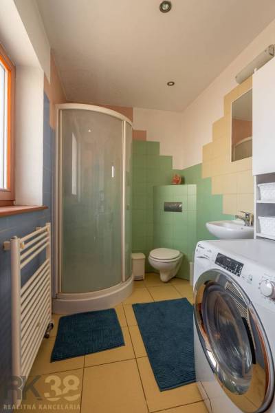 Predaj priestranného rodinného domu v historickej časti Popradu  - Kúpeľňa v rodinnom dome s práčkou, sprchovým kútom a farebnými dlaždicami.