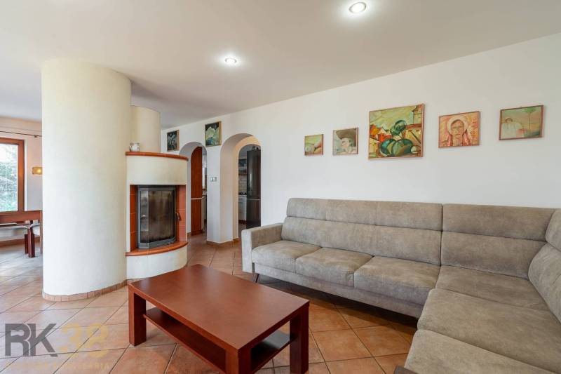 Predaj priestranného rodinného domu v historickej časti Popradu  - Obývačka rodinného domu s krbom, pohovkou a umeleckými obrazmi na stene.