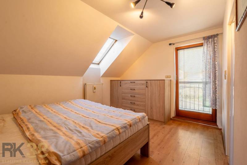 Predaj priestranného rodinného domu v historickej časti Popradu  - Spálňa s podlahou s dreveným dekorom a strešným oknom v rodinnom dome.