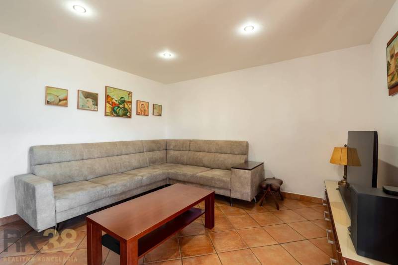 Predaj priestranného rodinného domu v historickej časti Popradu  - Obývacia izba v rodinnom dome s rohovou sedačkou a keramickou podlahou.