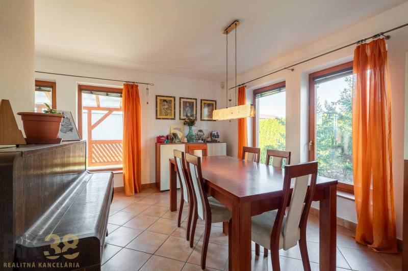 Predaj priestranného rodinného domu v historickej časti Popradu  - Interiér rodinného domu: jedáleň s veľkým stolom, stoličkami a klavírom.