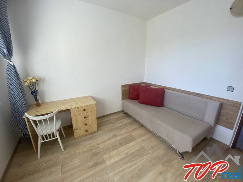 PRENÁJOM - 4 - izbový byt Košice - Západ, Obchodná ulica  - Obývacia izba v 4-izbovom byte so stolom, stoličkou a pohovkou. Podlaha s dreveným dekorom.