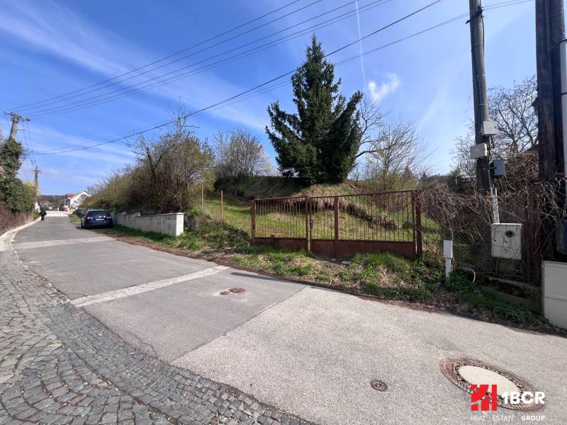 STAVEBNÝ POZEMOK S DUŠOU LEN PÁR MINÚT OD BRATISLAVY V OBCI MARIANKA - Pozemok na bývanie na Budovateľskej ulici v Marianke s bránou a príjazdovou cestou.