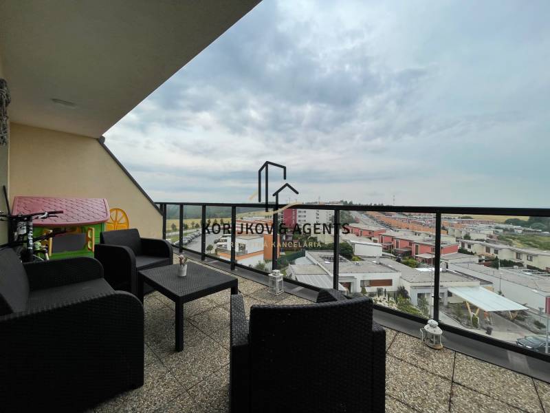 PREDAJ, 3 izb. byt v novostavbe PANORÁMA, 5 min. od AUPARKU - Balkón s výhľadom na ulici Borievkova, súčasť 3-izbového bytu, sedenie a detský domček.