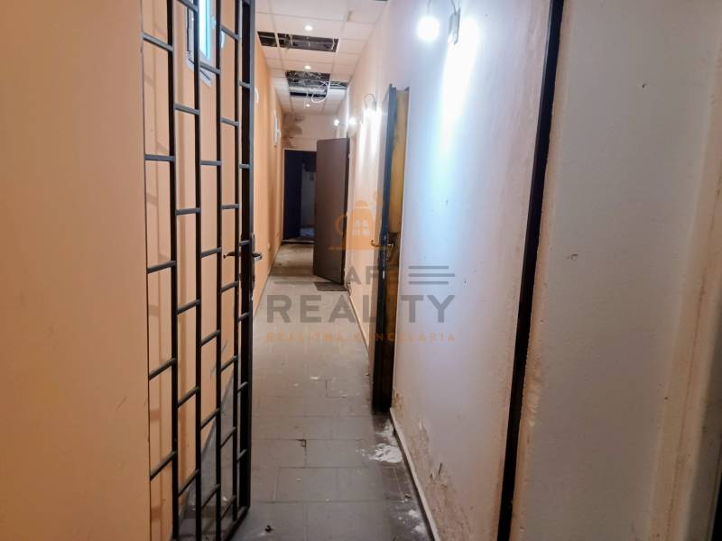 Na prenájom nebytový priestor o výmere 59 m², Bratislava, Štúrova - Úzky chodba s kovovou mrežou a osvetlením v obchodných priestoroch.