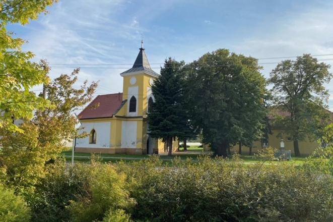 Práznovce – Spoluvlastnícky podiel na ornej pôde - Kostol obklopený zeleňou v Práznovciach na poľnohospodárskych a lesných pozemkoch.