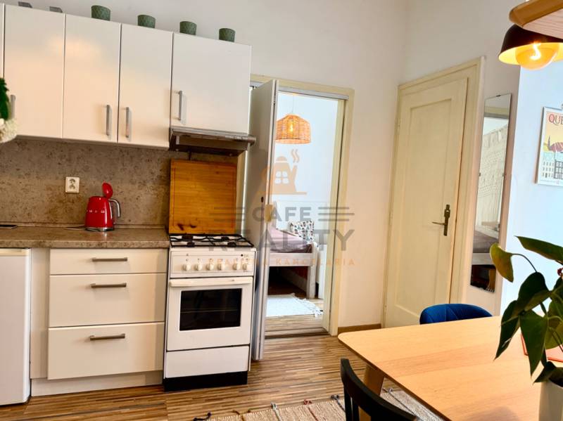 Na prenájom 2 izbový byt, Bratislava, Staré Mesto, Wilsonova ulica - Kuchyňa v 2-izbovom byte s podlahou s dreveným dekorom, jedálenským stolom a spotrebičmi.
