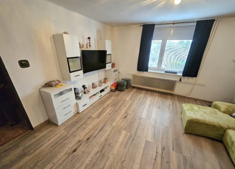 RODINNÝ DOM - HORNÉ OZOROVCE-POZEMOK 566 m2- 3,5 IZBOVÝ/ GARÁŽ - Obývačka v rodinnom dome s televíziou, bielym nábytkom a podlahou s dreveným dekorom.