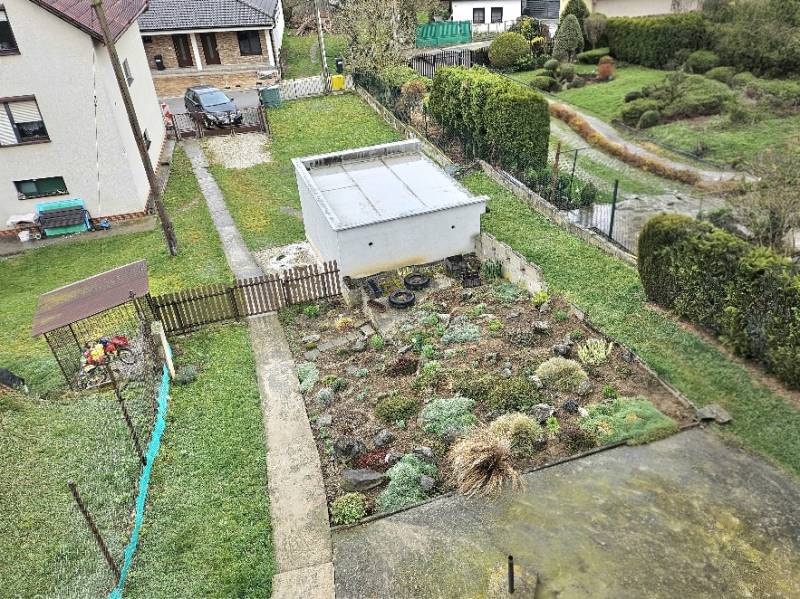 RODINNÝ DOM - HORNÉ OZOROVCE-POZEMOK 566 m2- 3,5 IZBOVÝ/ GARÁŽ - Rodinný dom v Horných Ozorovciach, Bánovce nad Bebravou, ukazuje záhradu so záhonom a garážou.