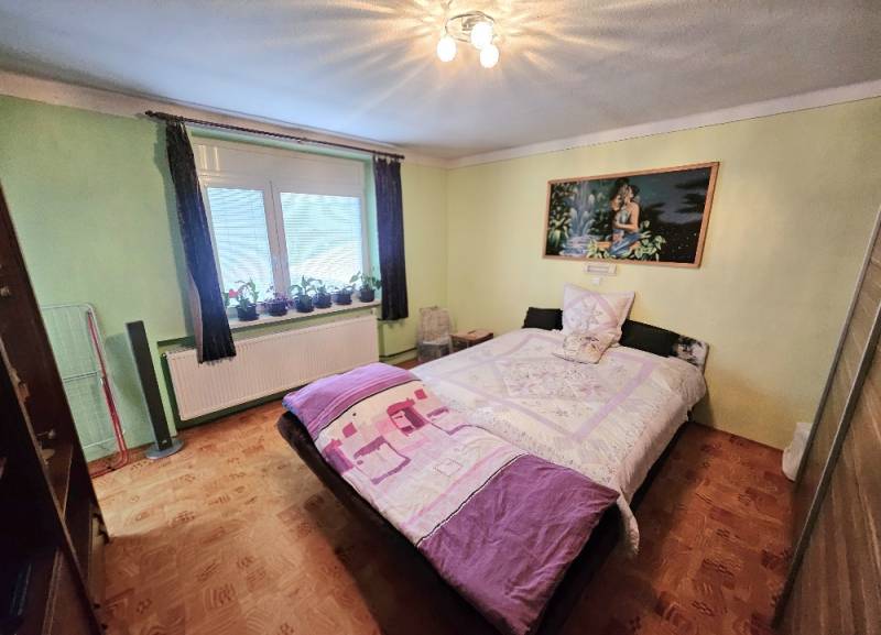 RODINNÝ DOM - HORNÉ OZOROVCE-POZEMOK 566 m2- 3,5 IZBOVÝ/ GARÁŽ - Spálňa v rodinnom dome s posteľou, zelenými stenami a podlahou s dreveným dekorom.