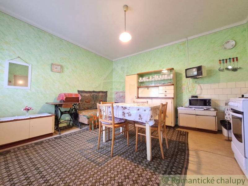 Pôvodný priestranný rodinný dom na rozľahlom pozemku v malebnej obci Ľ - Interiér rodinného domu s jedálenským stolom, kreslom a retro televíziou.