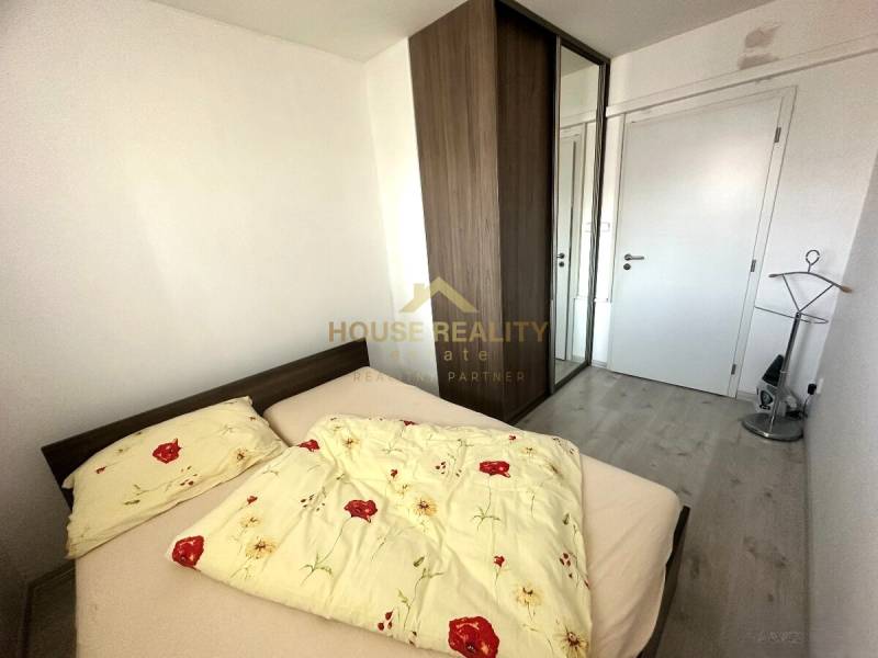 Prenájom pekný 2 izbový byt Šancová ulica, Bratislava III. Nové Mesto - Spálňa v 2-izbovom byte s posteľou, vstavanou skriňou a podlahou s dreveným dekorom.