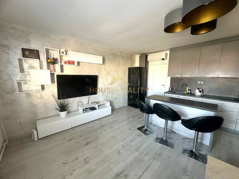 Prenájom pekný 2 izbový byt Šancová ulica, Bratislava III. Nové Mesto - Kuchyňa v 2-izbovom byte s televízorom, podlahou s dreveným dekorom a barovým pultom.