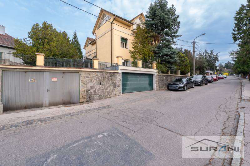 PRENÁJOM 4-IZBOVÉHO BYTU | ZÁHRADA | DVOJGARÁŽ | KRČMÉRYHO ULICA - Ulica Krčméryho v Bratislave - Staré Mesto s garážovým vjazdom a zaparkovanými autami.