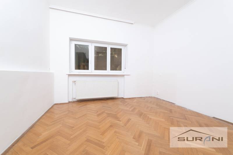 PRENÁJOM 4-IZBOVÉHO BYTU | ZÁHRADA | DVOJGARÁŽ | KRČMÉRYHO ULICA - Izba v 4-izbovom byte s bielymi stenami a podlahou s dreveným dekorom.