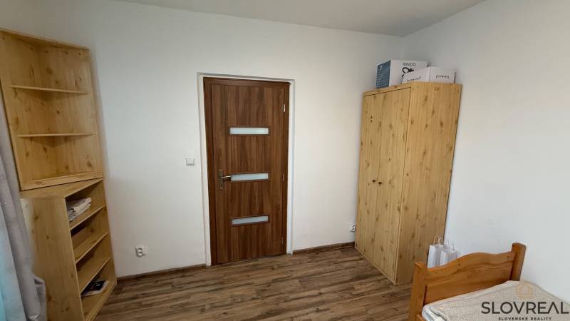 1-izbový byt na prenájom v Hliníku nad Hronom - Izba s dreveným dekorom, drevenými skriňami a posteľou v 1-izbovom byte.