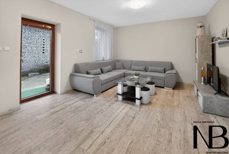 Rodinný dom s veľkým pozemkom a priestorom na podnikanie – T.Jastrabie - Obývacia izba v Rodinnom dome s podlahou s dreveným dekorom a rozkladacou sedačkou.