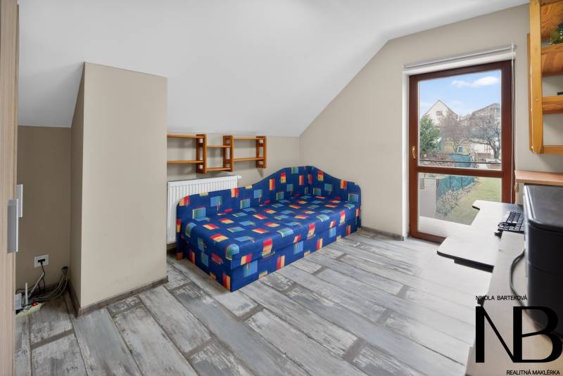 Rodinný dom s veľkým pozemkom a priestorom na podnikanie – T.Jastrabie - Podkrovná izba v rodinnom dome s farebnou pohovkou a výhľadom do záhrady.
