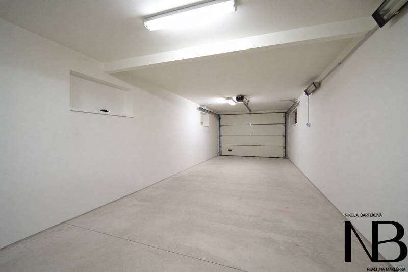 Rodinný dom s veľkým pozemkom a priestorom na podnikanie – T.Jastrabie - Priestranná garáž v rodinnom dome s bielymi stenami a betónovou podlahou.