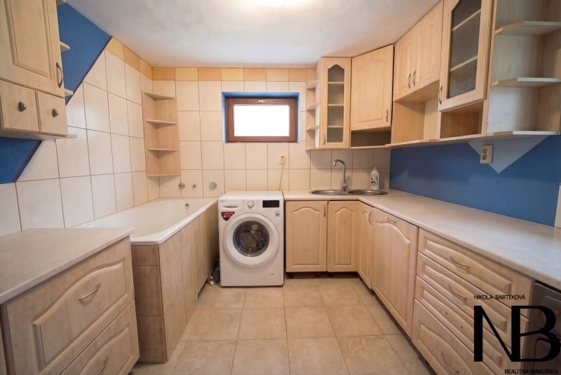 Rodinný dom s veľkým pozemkom a priestorom na podnikanie – T.Jastrabie - Kúpeľňa s vaňou, práčkou a kuchynskou linkou v rodinnom dome s modrým obkladom.