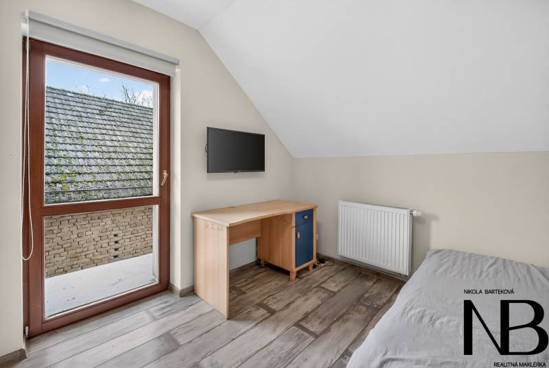 Rodinný dom s veľkým pozemkom a priestorom na podnikanie – T.Jastrabie - Jednoduchá izba v rodinnom dome s písacím stolom a televízorom na stene.