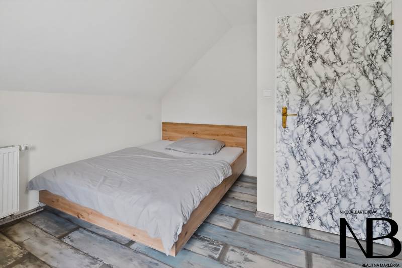 Rodinný dom s veľkým pozemkom a priestorom na podnikanie – T.Jastrabie - Spálňa v rodinnom dome s posteľou, radiátorom a dverami s mramorovým dekorom.