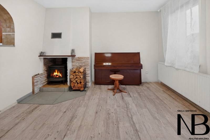 Rodinný dom s veľkým pozemkom a priestorom na podnikanie – T.Jastrabie - Krbu s drevom a klavírom dominuje rodinný dom s podlahou s dreveným dekorom.