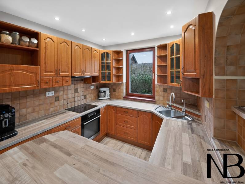 Rodinný dom s veľkým pozemkom a priestorom na podnikanie – T.Jastrabie - Kuchyňa v rodinnom dome s drevenými skrinkami a pracovnou doskou s dreveným dekorom.