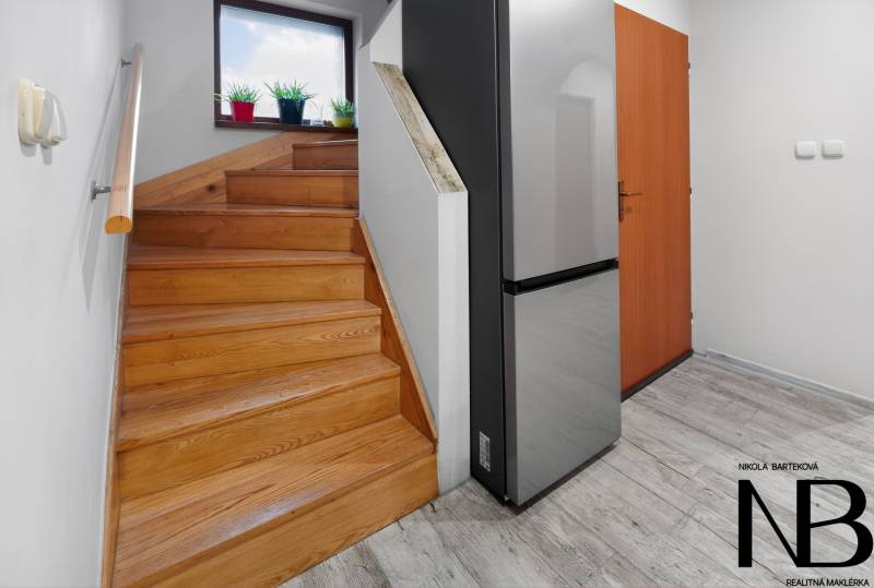 Rodinný dom s veľkým pozemkom a priestorom na podnikanie – T.Jastrabie - Drevené schody a chladnička s dreveným dekorom podlahy v rodinnom dome.