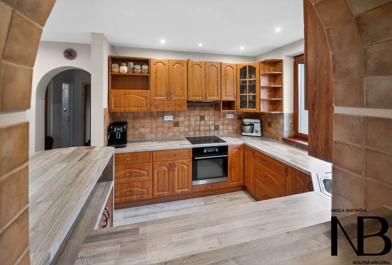 Rodinný dom s veľkým pozemkom a priestorom na podnikanie – T.Jastrabie - Kuchyňa v rodinnom dome s drevenými skrinkami a podlahou s dreveným dekorom.