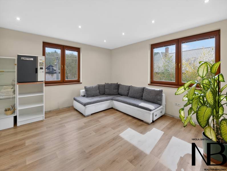 Rodinný dom s veľkým pozemkom a priestorom na podnikanie – T.Jastrabie - Obývacia izba s pohodlnou sedačkou, vitrínou a podlahou s dreveným dekorom v rodinnom dome.