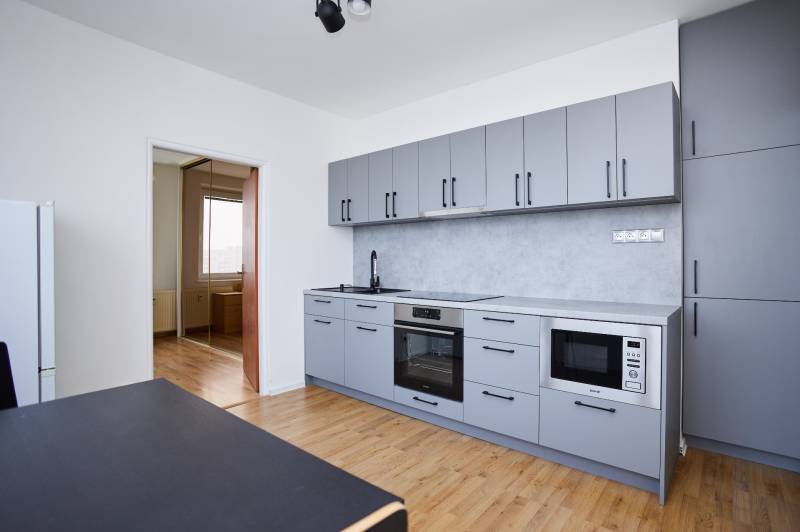 NA PREDAJ-3-izbový byt s loggiou a výhľadom na centrum mesta, KE-JUH - Kuchyňa v 3-izbovom byte s modernými spotrebičmi a podlahou s dreveným dekorom.