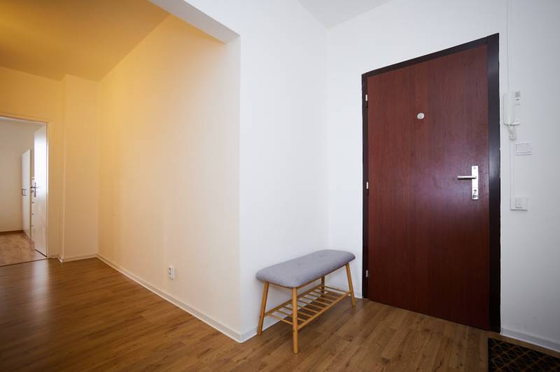 NA PREDAJ-3-izbový byt s loggiou a výhľadom na centrum mesta, KE-JUH - Vstupná hala s podlahou s dreveným dekorom a lavicou v 3-izbovom byte.