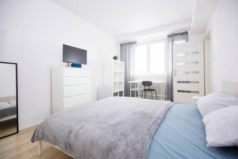 NA PREDAJ,2-IZBOVÝ TEHLOVÝ BYT,KOŠICE-SEVER,LOMNICKÁ UL. - Svetlá spálňa s posteľou, zrkadlom, komodou a podlahou s dreveným dekorom.