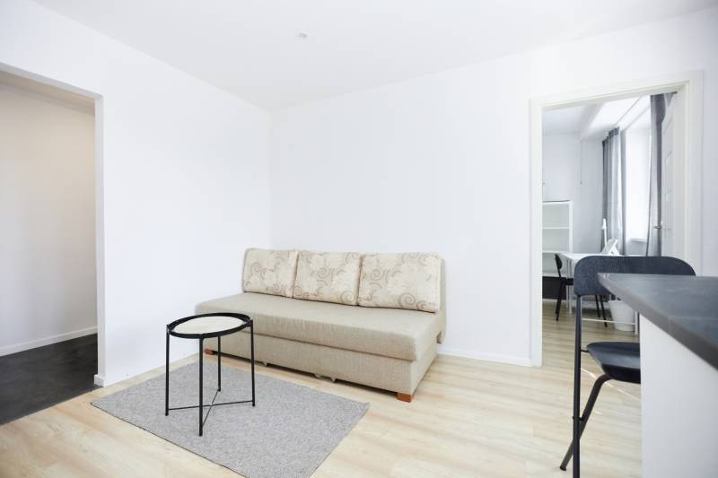 NA PREDAJ,2-IZBOVÝ TEHLOVÝ BYT,KOŠICE-SEVER,LOMNICKÁ UL. - Obývací priestor s pohovkou, stolíkom a podlahou s dreveným dekorom v 2-izbovom byte.