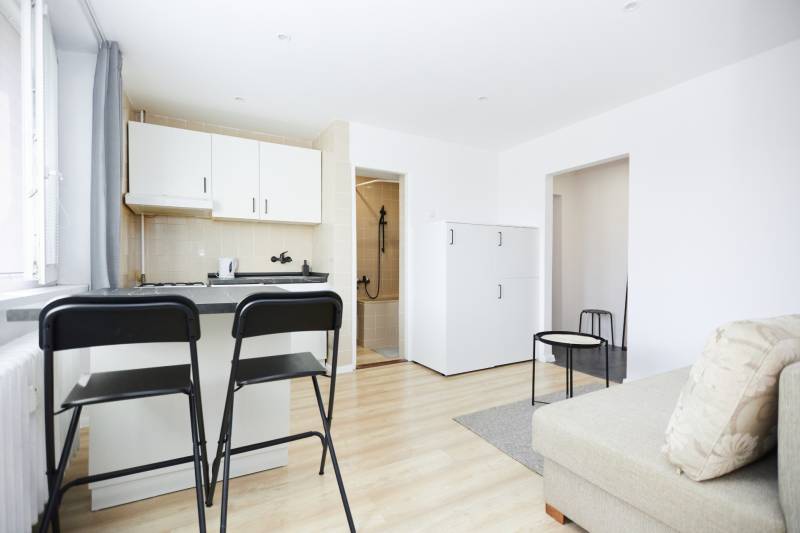 NA PREDAJ,2-IZBOVÝ TEHLOVÝ BYT,KOŠICE-SEVER,LOMNICKÁ UL. - Interiér 2-izbového bytu s kuchyňou, barovými stoličkami a podlahou s dreveným dekorom.