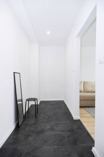 NA PREDAJ,2-IZBOVÝ TEHLOVÝ BYT,KOŠICE-SEVER,LOMNICKÁ UL. - Úzka chodba v 2-izbovom byte s čiernou podlahou a zrkadlom.