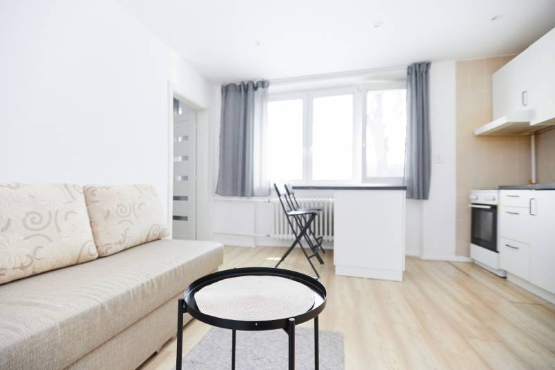 NA PREDAJ,2-IZBOVÝ TEHLOVÝ BYT,KOŠICE-SEVER,LOMNICKÁ UL. - Obývacia izba v 2-izbovom byte s pohovkou a podlahou s dreveným dekorom.