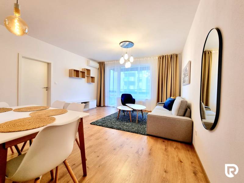 REZERVOVANÉ I Posledný investičný krásny 2-izbový byt | 62 m² | - Obývačka v 2-izbovom byte s podlahou s dreveným dekorom, pohodlnou sedačkou a jedálenským stolom.