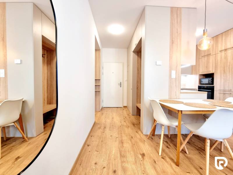 REZERVOVANÉ I Posledný investičný krásny 2-izbový byt | 62 m² | - Interiér 2-izbového bytu s podlahou s dreveným dekorom a štýlovým nábytkom.