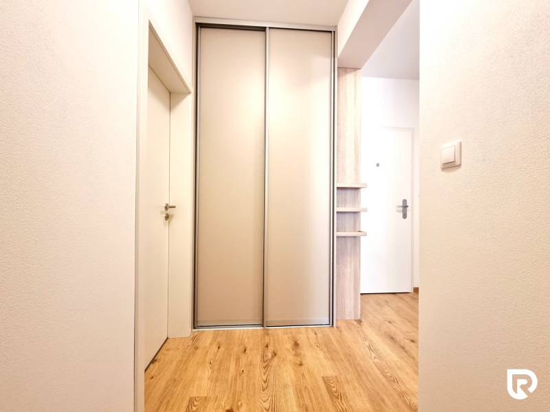 REZERVOVANÉ I Posledný investičný krásny 2-izbový byt | 62 m² | - Chodba 2-izbového bytu s posuvnými dverami a podlahou s dreveným dekorom.