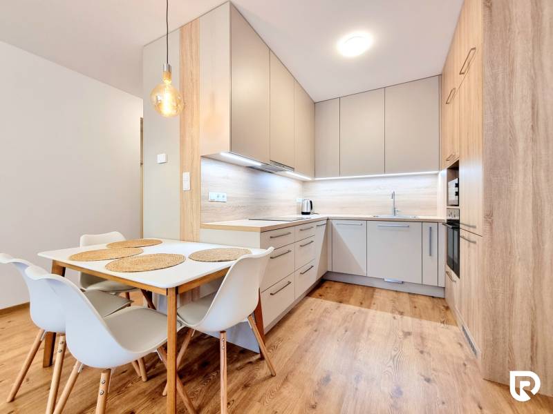 REZERVOVANÉ I Posledný investičný krásny 2-izbový byt | 62 m² | - Kuchyňa v 2-izbovom byte s podlahou s dreveným dekorom a jedálenským stolom.