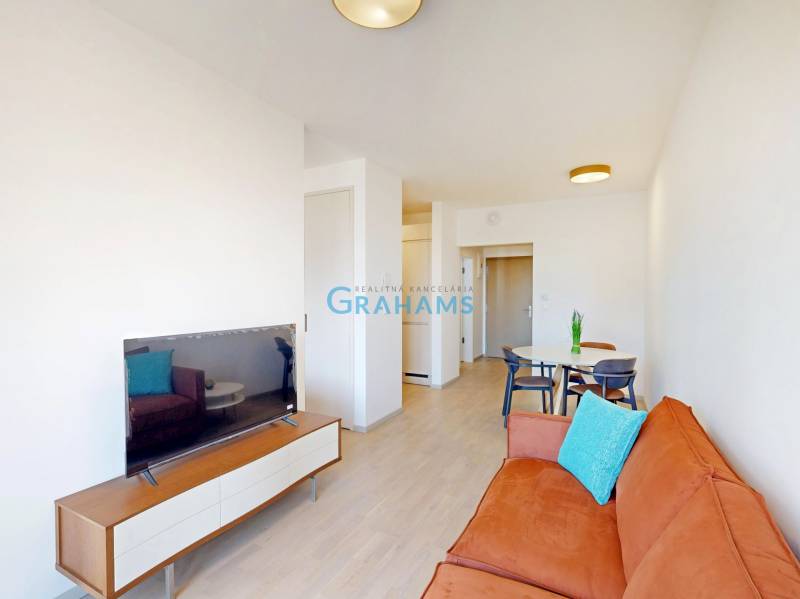 Nový, ešte neobývaný 1,5-izbový byt, parkovanie, Metropolis, Bottova - Obývačka s oranžovou sedačkou, jedálenským stolom a podlahou s dreveným dekorom v 2-izbovom byte.