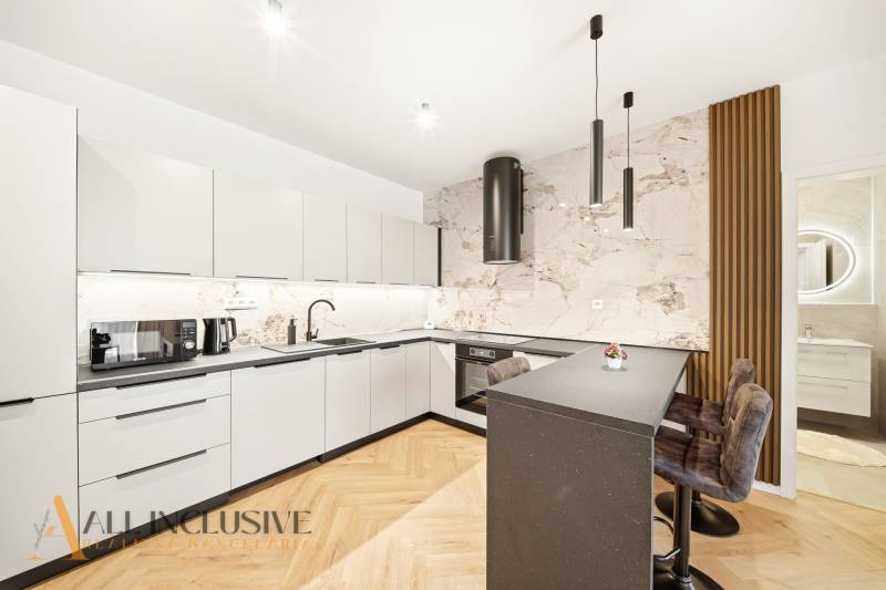 Na prenájom 2-izb. byt s terasou, Dun. Streda -Florida - Kuchyňa s bielymi skriňami, ostrovčekom a podlahou s dreveným dekorom v 4-izbovom byte.