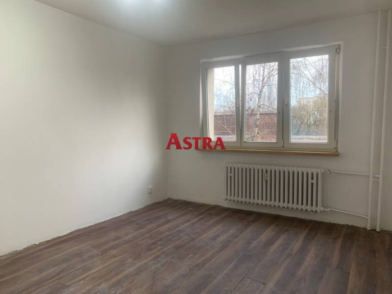 2 IZBOVÝ BYT, KOŠICE – ŠIRŠIE CENTRUM - Izba s bielymi stenami, podlahou s dreveným dekorom a veľkým oknom v 2-izbovom byte.