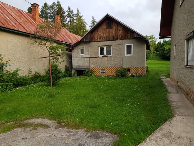 PREDAJ – Rodinný dom s druhou samostatnou stavbou, garážou  - Rodinný dom v Blatnici s predzáhradkou a tehlovou strechou, obklopený zelenou trávou.