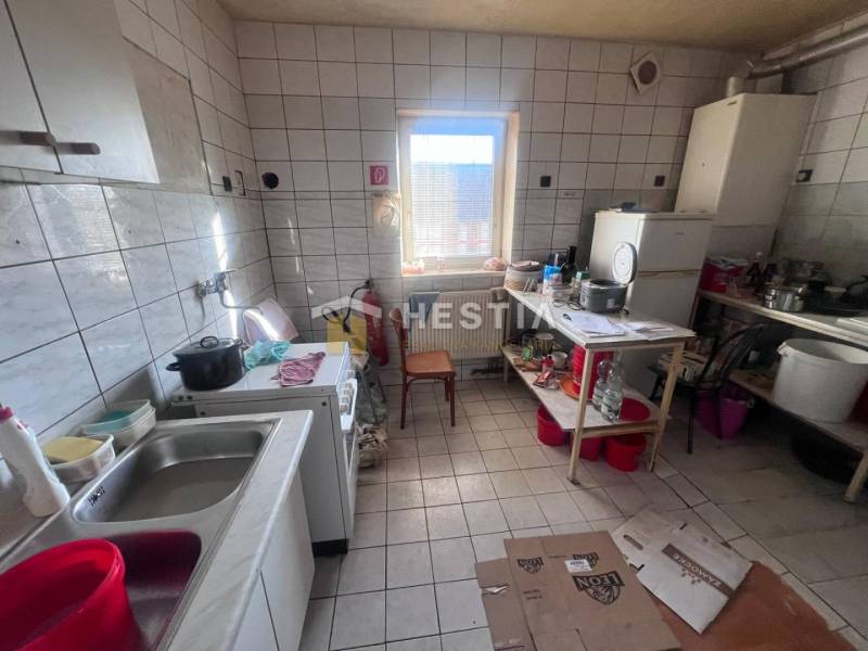 Na predaj rodinný dom, gastro prevádzka – Senica, Robotnícka ulica - Kuchyňa s podlahou z dlaždíc, sporákom a riadmi na poličke, gastro priestory.